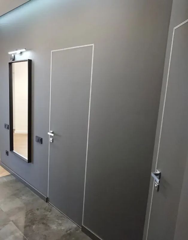 Скрытая дверь под покраску в прихожей рядом с зеркалом — фото с объекта BAKUN DOORS
